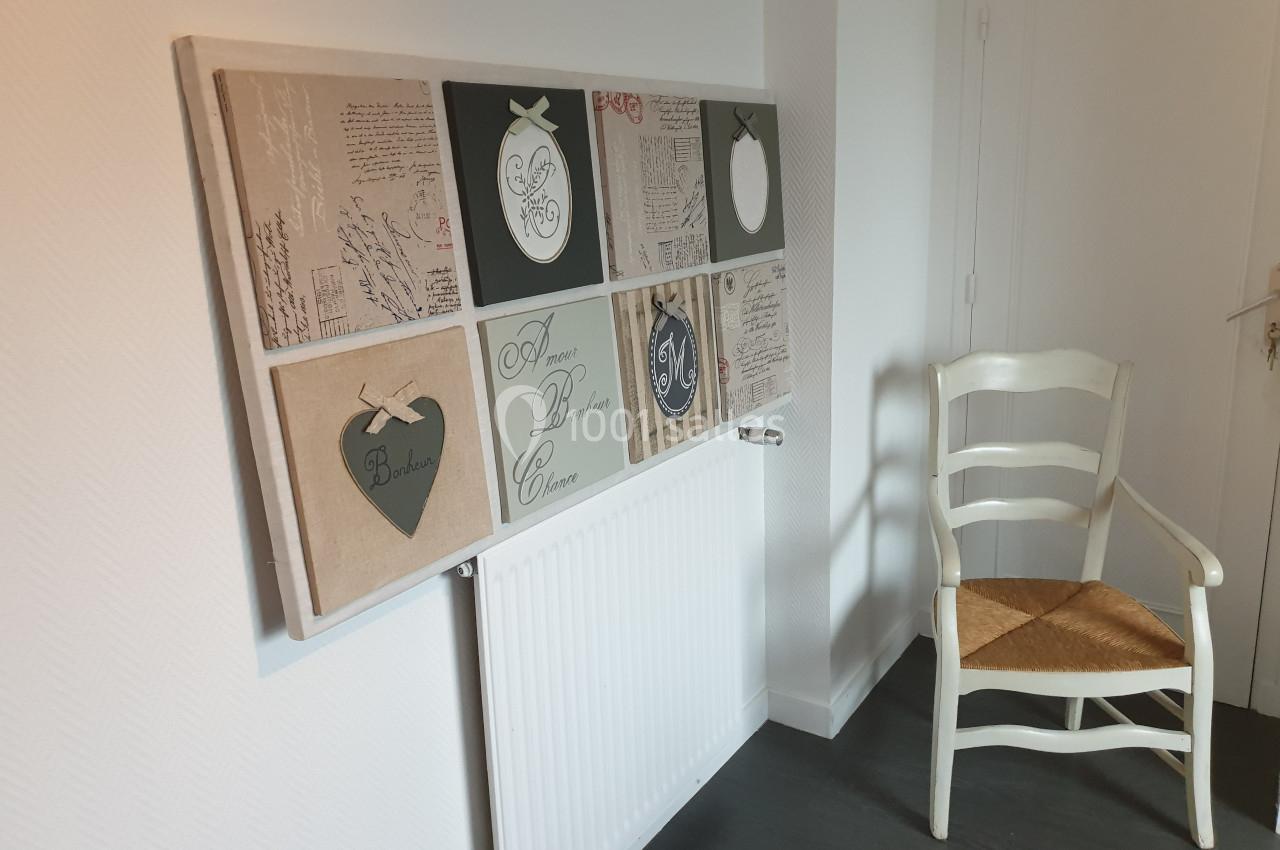 Tableau décoratif composé de cadres variés au-dessus d'un radiateur, avec une chaise en bois à droite.