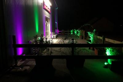 Table ronde élégamment dressée avec nappes blanches, assiettes, couverts, verres et serviettes ornées d'anneaux dorés.