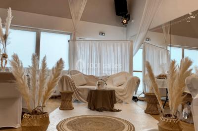 Table ronde élégamment dressée avec nappes blanches, assiettes, couverts, verres et serviettes ornées d'anneaux dorés.