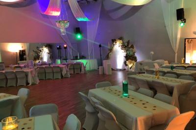 Table ronde élégamment dressée avec nappes blanches, assiettes, couverts, verres et serviettes ornées d'anneaux dorés.