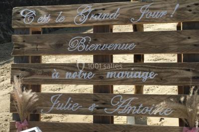 Centre de table avec bouquet de fleurs blanches et roses, numéro de table ’1’ et bougies sur une nappe blanche.