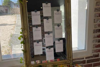 Centre de table avec bouquet de fleurs blanches et roses, numéro de table ’1’ et bougies sur une nappe blanche.