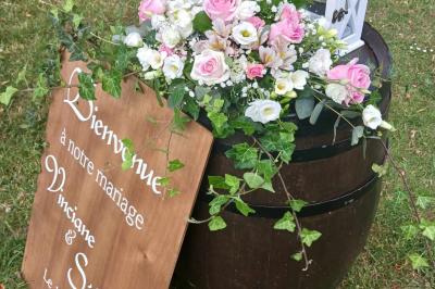 Centre de table avec bouquet de fleurs blanches et roses, numéro de table ’1’ et bougies sur une nappe blanche.