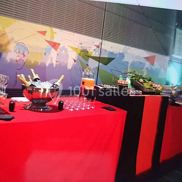 Buffet avec nappes rouges, seaux à champagne, verres, distributeur de boisson et plateau de nourriture variée.