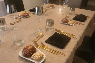 Table élégamment dressée avec nappes blanches, chaises assorties, chandeliers, fleurs roses et couverts dorés.