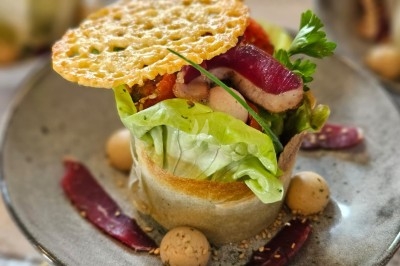 Table élégamment dressée avec nappes blanches, chaises assorties, chandeliers, fleurs roses et couverts dorés.