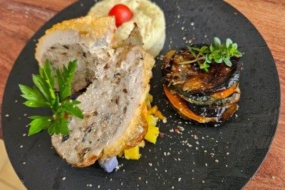 Table élégamment dressée avec nappes blanches, chaises assorties, chandeliers, fleurs roses et couverts dorés.