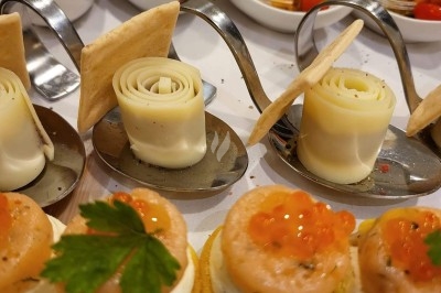 Table élégamment dressée avec nappes blanches, chaises assorties, chandeliers, fleurs roses et couverts dorés.