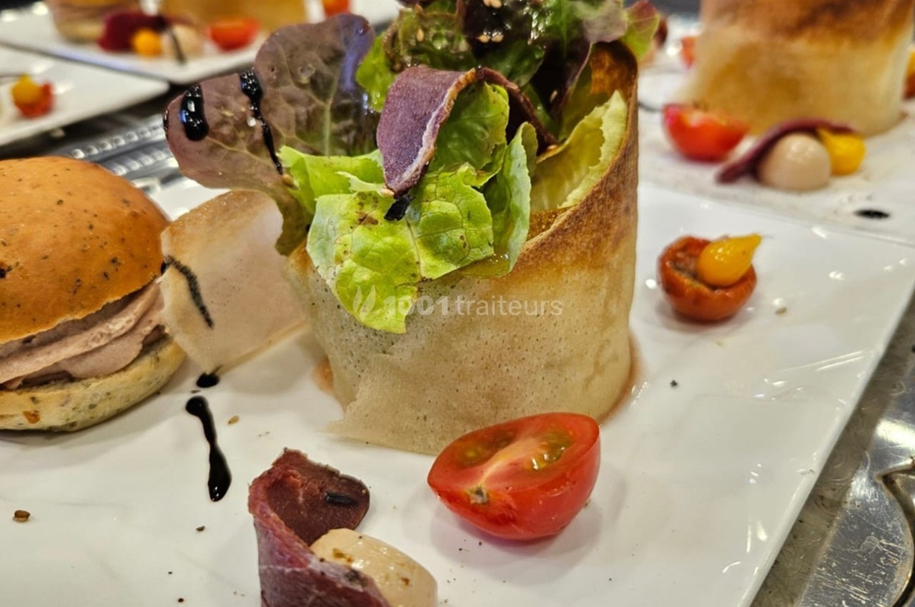 Assiette composée d'une salade en corolle de pâte croustillante, tomates cerises et garnitures variées.