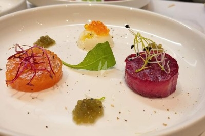 Table dressée avec nappe orange, couverts, verres, bouteilles et assiettes, disposée pour un repas ou une réunion.