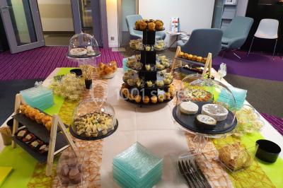 Table élégamment dressée avec nappes blanches, chaises assorties, chandeliers, fleurs roses et couverts dorés.