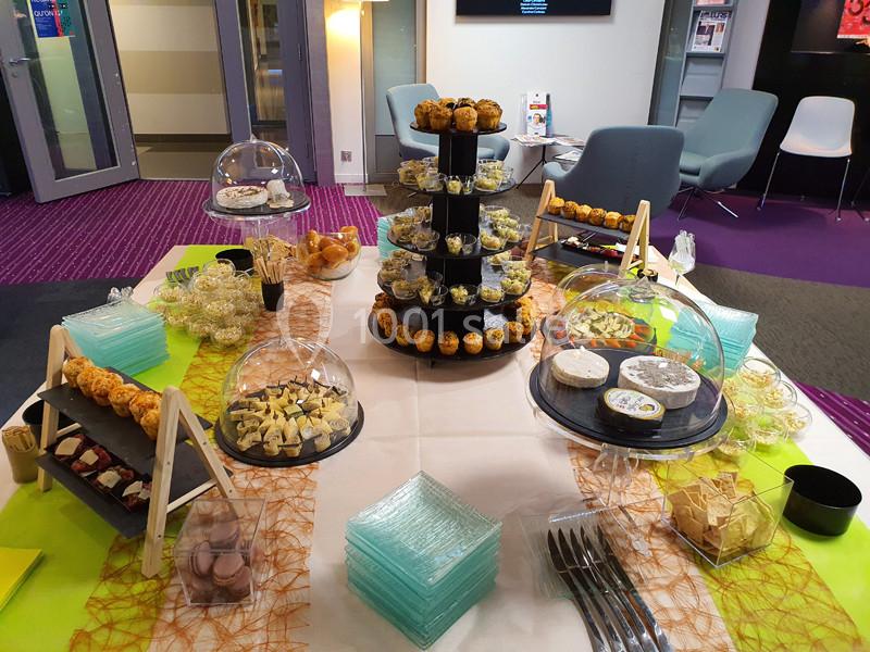 Buffet varié avec amuse-bouches, fromages, desserts et verrines disposés sur une table décorée.