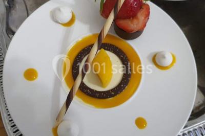 Table élégamment dressée avec nappes blanches, chaises assorties, chandeliers, fleurs roses et couverts dorés.