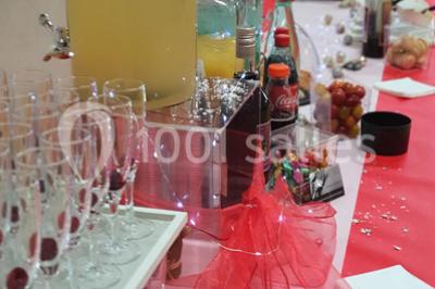 Table élégamment dressée avec nappes blanches, chaises assorties, chandeliers, fleurs roses et couverts dorés.