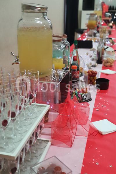 Table dressée pour un buffet avec boissons, verres, bonbons et décorations rouges.