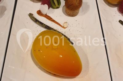 Table élégamment dressée avec nappes blanches, chaises assorties, chandeliers, fleurs roses et couverts dorés.