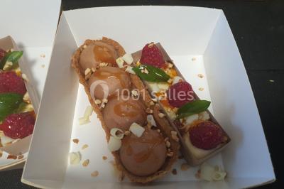 Table élégamment dressée avec nappes blanches, chaises assorties, chandeliers, fleurs roses et couverts dorés.