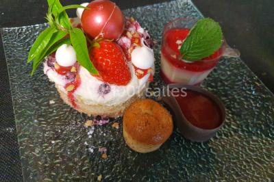 Table élégamment dressée avec nappes blanches, chaises assorties, chandeliers, fleurs roses et couverts dorés.