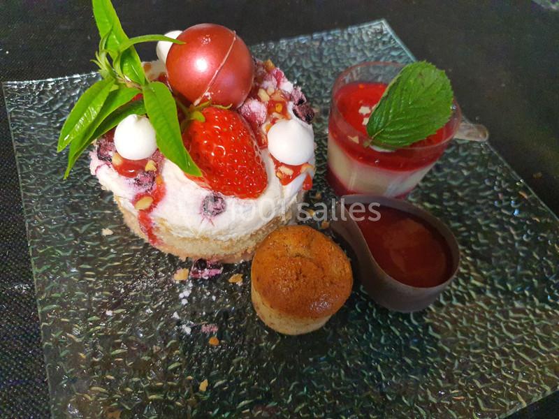 Dessert composé d'un entremets aux fruits rouges, d'une verrine, d'un coulis et d'un petit gâteau sur une assiette en verre.