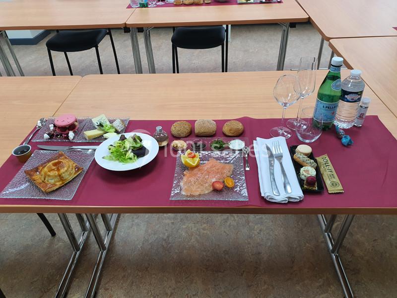 Repas dressé sur une table avec entrée, salade, pain, saumon fumé, desserts, couverts et boissons.