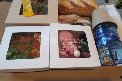 Table élégamment dressée avec nappes blanches, chaises assorties, chandeliers, fleurs roses et couverts dorés.