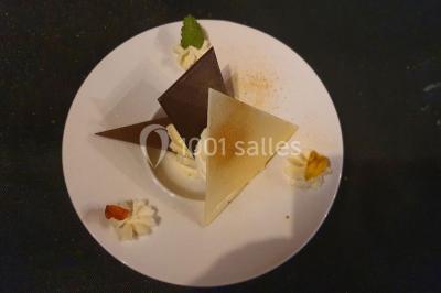 Table élégamment dressée avec nappes blanches, chaises assorties, chandeliers, fleurs roses et couverts dorés.