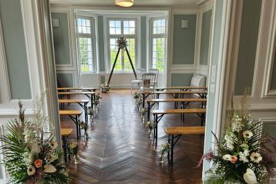 Table élégamment dressée avec nappes blanches, chaises assorties, chandeliers, fleurs roses et couverts dorés.