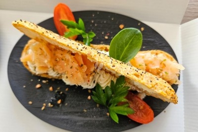 Table élégamment dressée avec nappes blanches, chaises assorties, chandeliers, fleurs roses et couverts dorés.