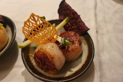 Table élégamment dressée avec nappes blanches, chaises assorties, chandeliers, fleurs roses et couverts dorés.
