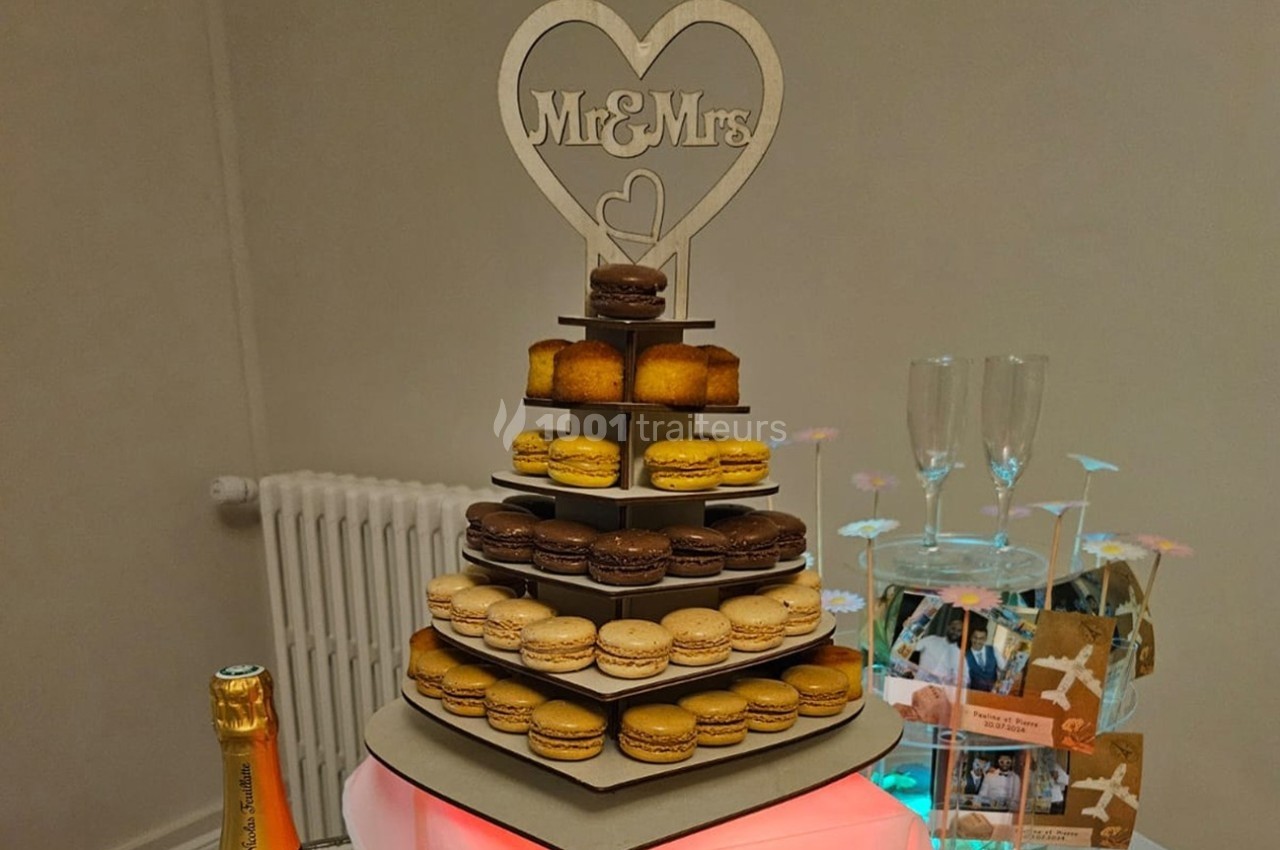 Tour de macarons et petits gâteaux sur un présentoir décoré d'un cœur ’Mr & Mrs’, entourée d'éléments de fête.
