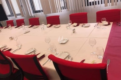 Table dressée avec nappe orange, couverts, verres, bouteilles et assiettes, disposée pour un repas ou une réunion.