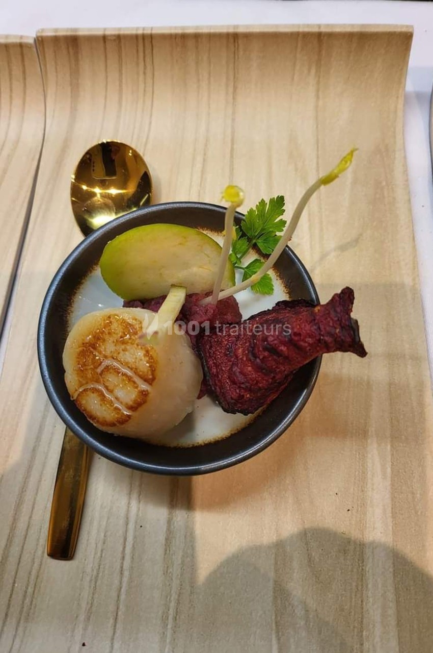 Plat gastronomique composé d'une noix de Saint-Jacques, d'une chips de betterave, d'une pomme verte et d'une herbe…