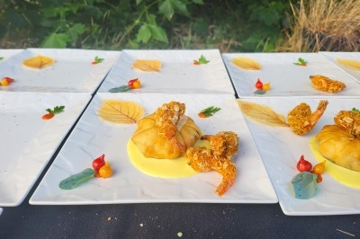 Table dressée avec nappe orange, couverts, verres, bouteilles et assiettes, disposée pour un repas ou une réunion.