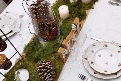 Table dressée avec nappe orange, couverts, verres, bouteilles et assiettes, disposée pour un repas ou une réunion.
