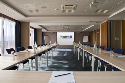 Plateau de fromages variés avec des fruits, dont des raisins, des fraises et un ananas au centre, présenté sur un tonneau.