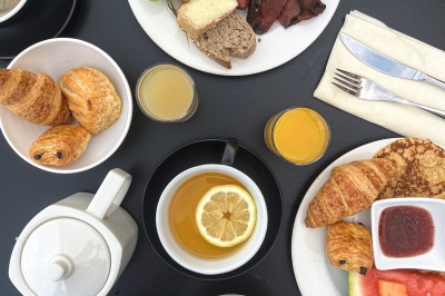 Plateau de fromages variés avec des fruits, dont des raisins, des fraises et un ananas au centre, présenté sur un tonneau.