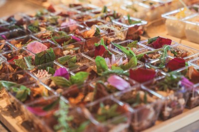 Plateau de fromages variés avec des fruits, dont des raisins, des fraises et un ananas au centre, présenté sur un tonneau.