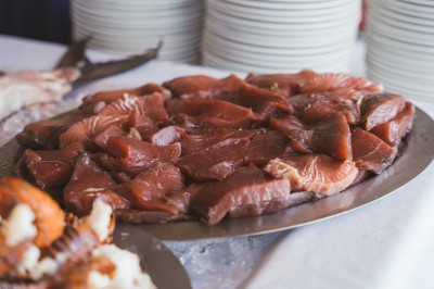 Plateau de fromages variés avec des fruits, dont des raisins, des fraises et un ananas au centre, présenté sur un tonneau.