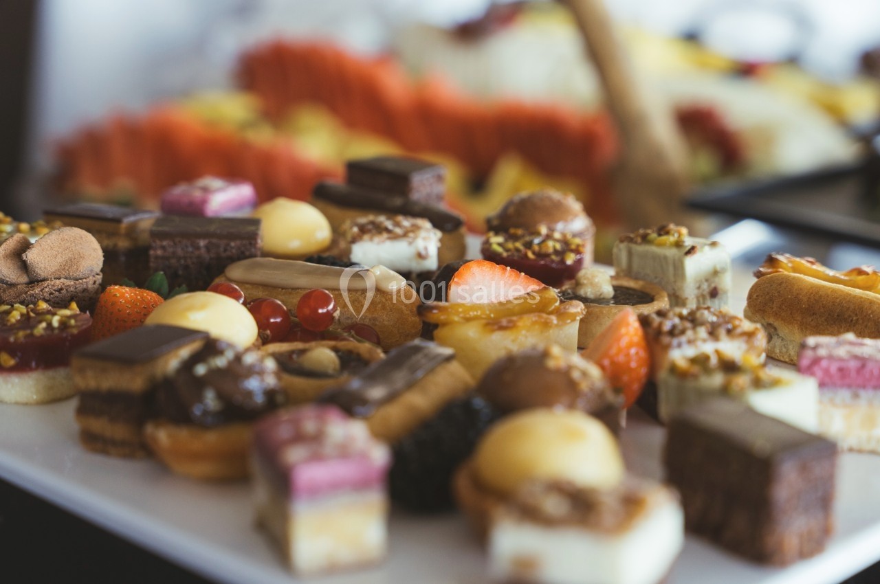 Assortiment de petits desserts variés disposés sur un plateau, avec des fruits et des pâtisseries colorées.