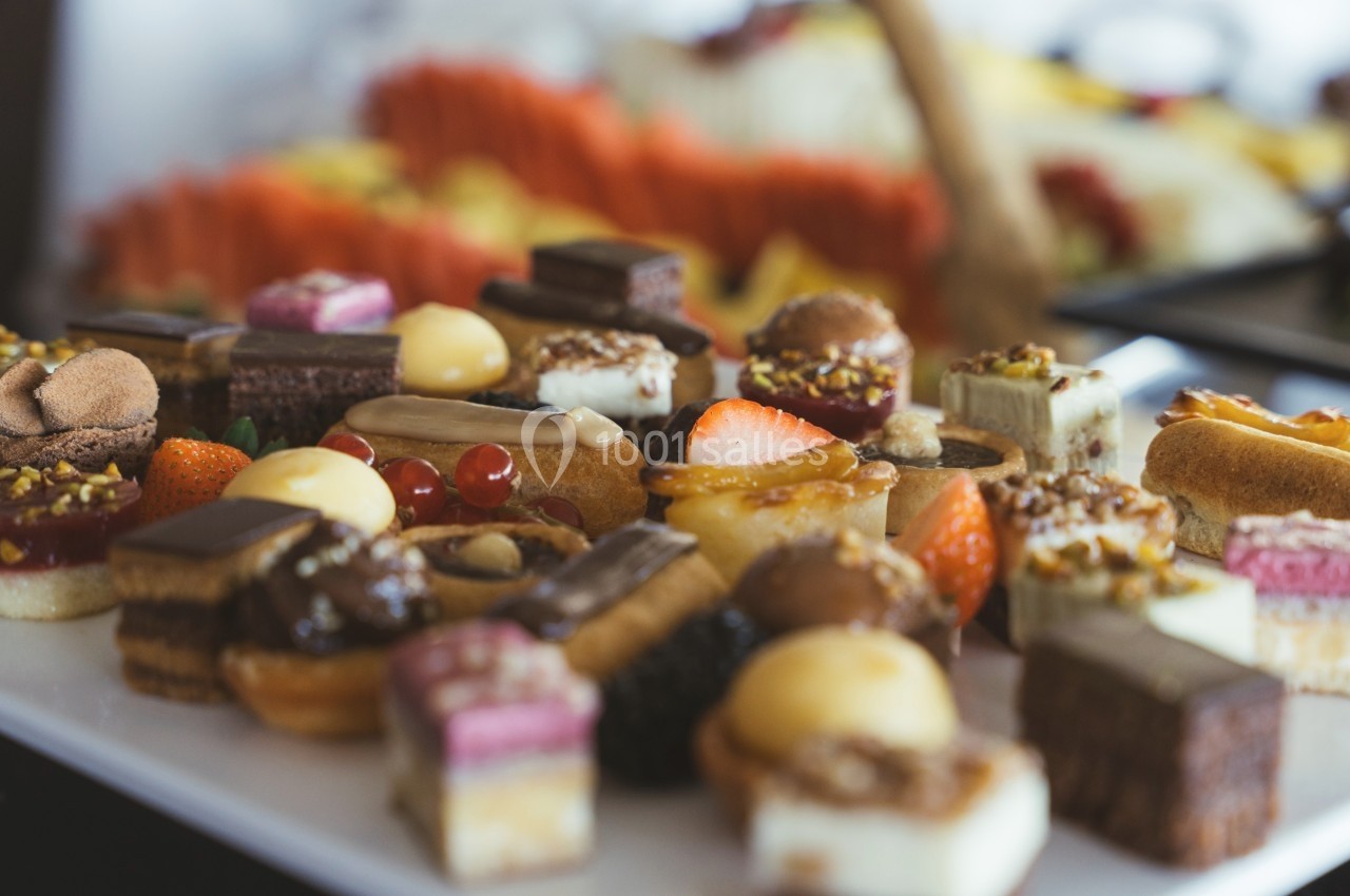 Plateau de petits desserts variés, incluant des pâtisseries, fruits et chocolats, disposés sur une table.