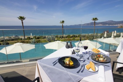 Chambre lumineuse avec lit double, mobilier moderne et vue sur la mer depuis une grande baie vitrée.