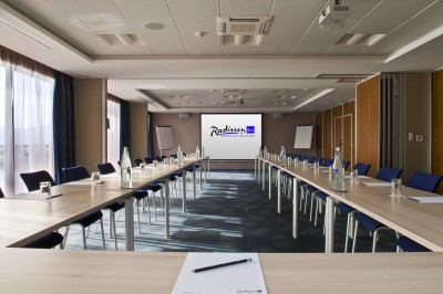 Chambre lumineuse avec lit double, mobilier moderne et vue sur la mer depuis une grande baie vitrée.