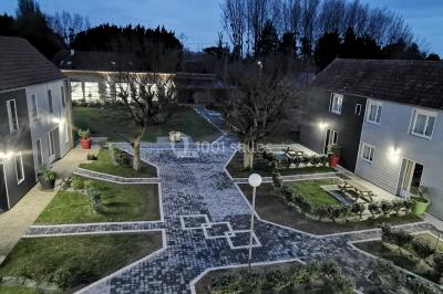 Étang entouré d'arbres illuminés la nuit, avec leurs reflets visibles sur l'eau calme.