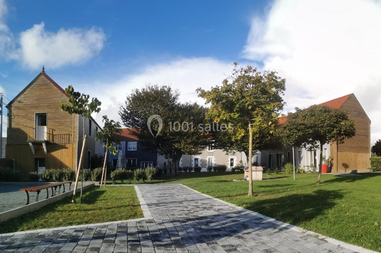 Bâtiments modernes et traditionnels entourés d'arbres, avec une allée pavée et un espace vert au premier plan.