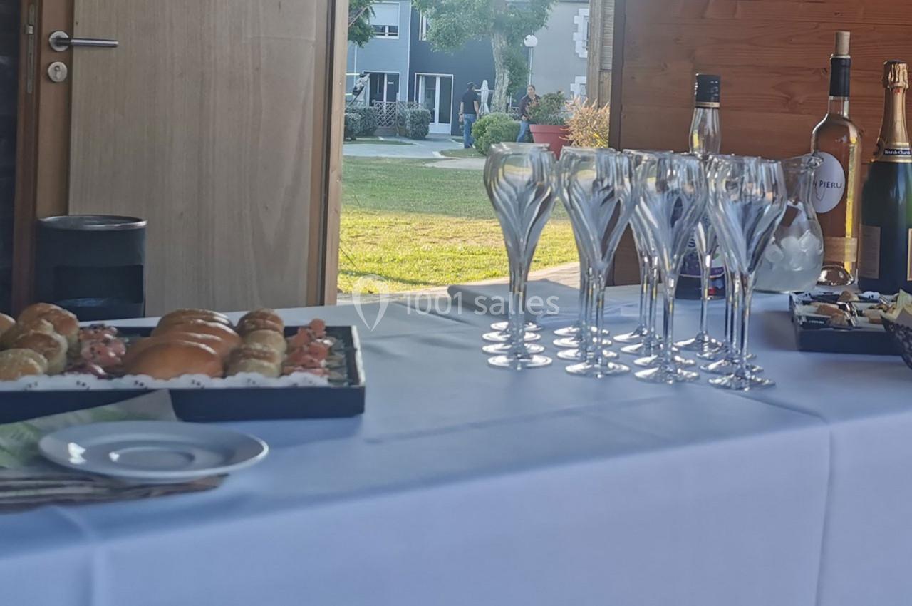 Plateau de viennoiseries et flûtes à champagne disposés sur une table blanche, avec un jardin en arrière-plan.