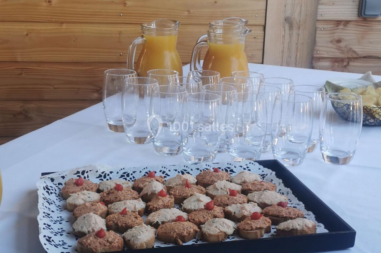 Plateau de biscuits décorés devant des verres vides et deux carafes de jus d'orange sur une table en bois.