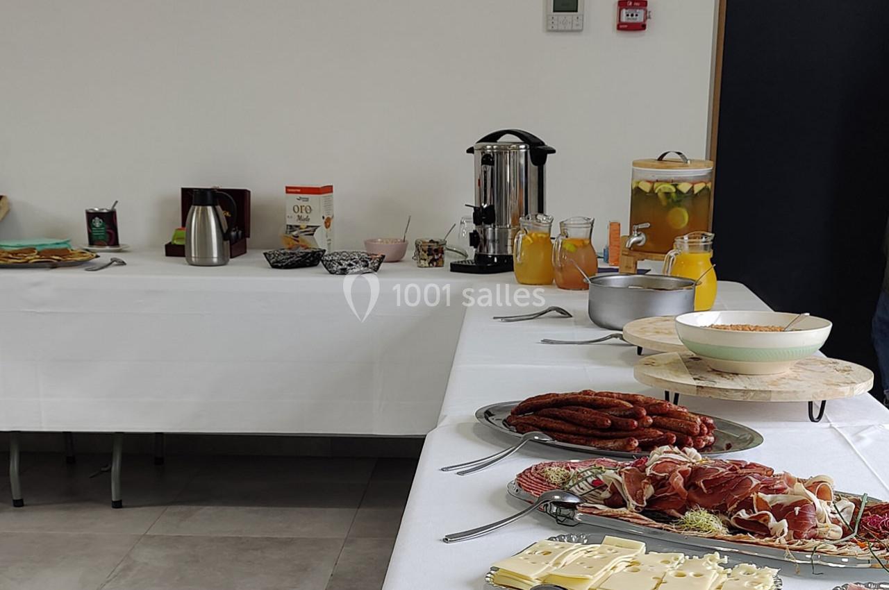 Buffet avec charcuterie, fromage, boissons chaudes et froides, disposé sur des tables couvertes de nappes blanches.