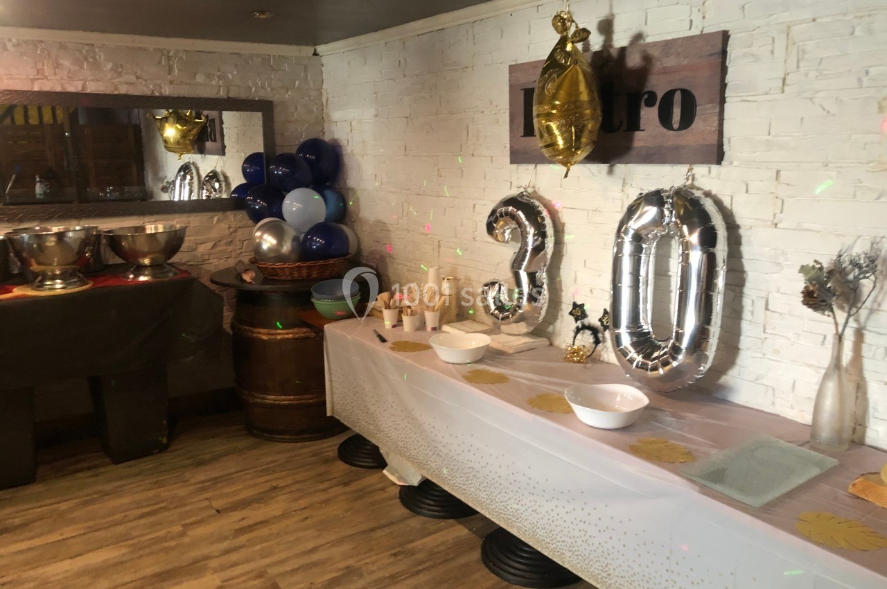 Décoration d'anniversaire avec ballons ’30’, table dressée et mur en briques blanches dans une salle festive.