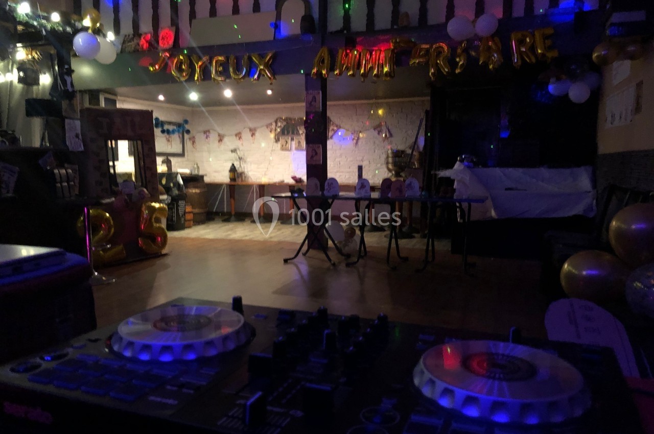 Salle décorée pour un anniversaire avec ballons, guirlandes lumineuses et une table de mixage au premier plan.