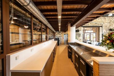Tables dressées avec nappes blanches et chaises en bois sous des voiles d'ombrage dans une cour extérieure ensoleillée.